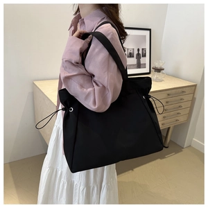 Detail of black large capacity tote bag with drawstring features and nylon texture
