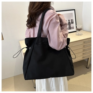 Detailed view of black canvas tote bag with side drawstring details on model