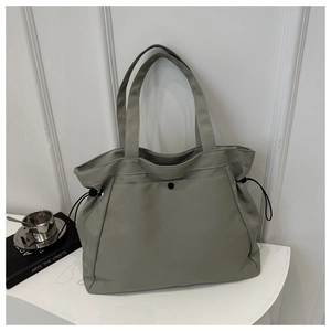 Detail of grey minimalist nylon tote bag featuring side drawstrings and snap closure