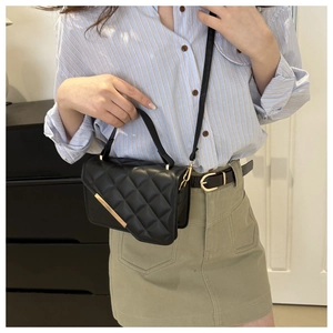 Détail d'un sac à bandoulière en cuir PU noir matelassé avec barre métallique dorée