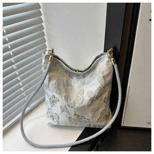 Detailed embroidery of gold and blue butterflies on a white bucket bag with braided strap