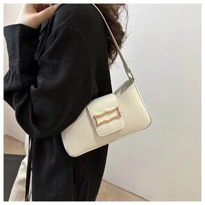Close-up of white leather underarm bag featuring a modern gold irregular buckle