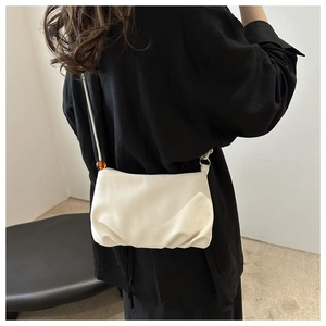 Gros plan d'un sac nuage blanc avec texture plissée douce et détail de perle ambrée
