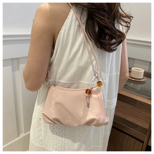 Gros plan du sac en satin rose clair avec texture plissée élégante et perles ambrées