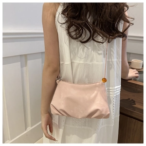 Détail du sac nuage rose clair avec texture en cuir lisse et perle décorative orange