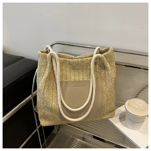Close-up of beige woven tote bag with cotton rope handles and leather pocket detail
