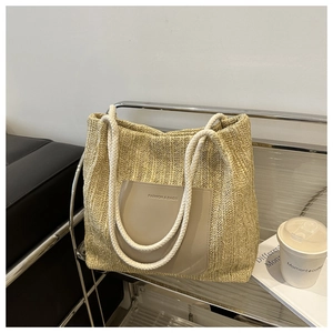 Detail of woven straw tote bag featuring leather front pocket and rope handles for summer