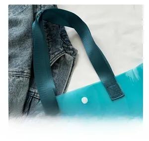 Detail of teal translucent PVC tote bag with durable nylon handles and white snap button