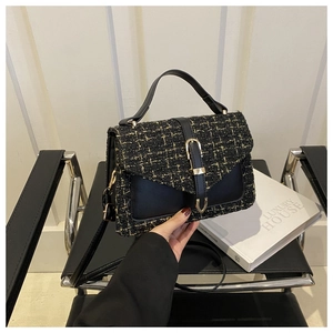 Detail of tweed and black leather handbag with gold buckle and adjustable strap