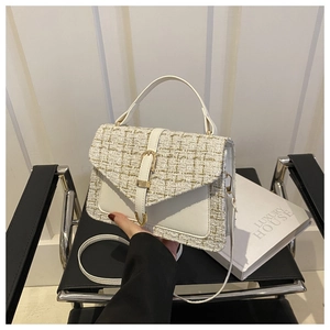 Close-up of white tweed handbag featuring gold U-shaped buckle and elegant PU leather trim