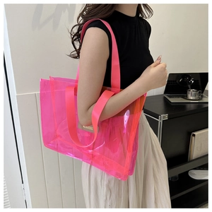 Detail of neon pink transparent PVC travel tote bag with branded leather label