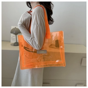 Side view of bright orange clear PVC tote bag with MS. JUNXIBAG patch on shoulder