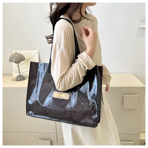 Macro detail of high-gloss black tote bag showing beige MS. HUIXIBAG brand leather patch