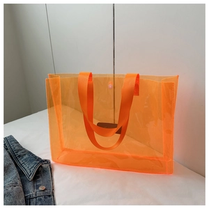 Close-up of orange translucent PVC tote bag with reinforced handles and leather tag
