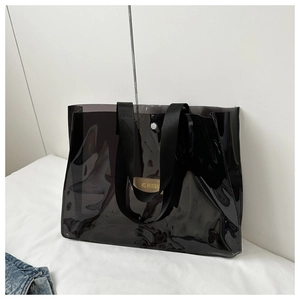 Detail of semi-transparent black PVC tote bag featuring a beige leather label and metal buckle