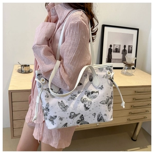 Détail du sac cabas blanc à motif papillon montrant l'imprimé artistique et le cordon latéral