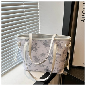 Gros plan sur les motifs de papillons et le cordon latéral d'un grand sac cabas blanc