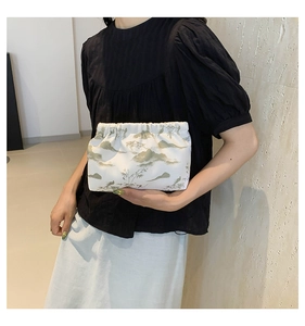 Detail of a Chinese landscape ink painting on a soft white pleated cloud clutch bag