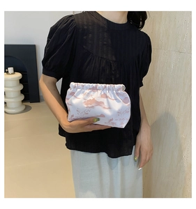 Detail of white fabric pouch with pink oriental cloud patterns held by a model