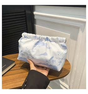 Close-up of soft pleated cloud-print clutch bag with elegant landscape bird patterns