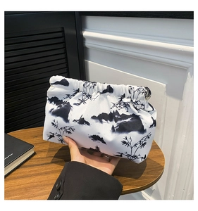 Detail of artistic ink landscape print on white fabric clutch bag with metal clasp