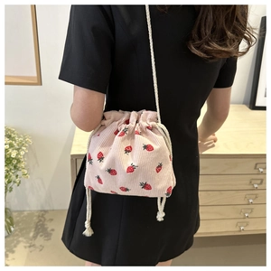 Détail du mannequin portant un sac seau en velours côtelé avec imprimé fraise