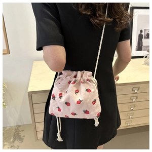 Close-up of pink corduroy bucket bag with strawberry print and cotton rope strap