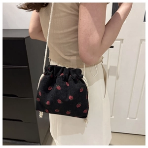 Detail of strawberry print corduroy drawstring bag showing texture and white cotton strap