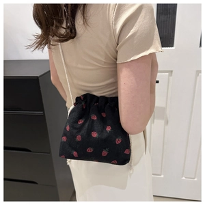 Detail of black corduroy bucket bag with strawberry print and cotton rope strap