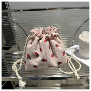 Detail of pink corduroy bucket bag featuring red strawberry prints and white cotton drawstrings
