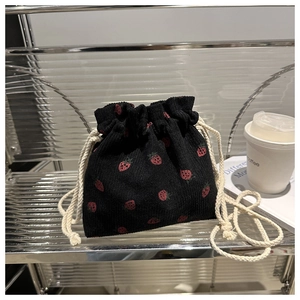 Detail of strawberry print on black corduroy bucket bag with drawstring closure