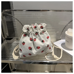 Detail of corduroy drawstring bag featuring red strawberry print and cotton rope closure
