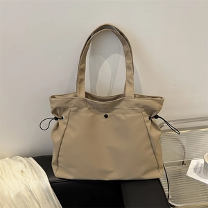 Minimalist beige nylon tote bag with black drawstring details for daily commute fashion