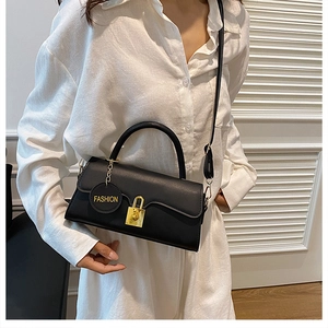 Close-up of matte black leather bag with gold square lock and round fashion tag