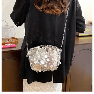 Detail of silver sequin square bag with chain strap on model in a modern indoor setting