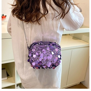 Close-up of a stylish purple sequin crossbody bag with silver metal chain on a model