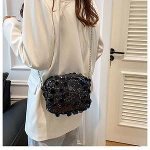 Close-up of sparkling dark blue sequin crossbody bag with silver chain strap worn on waist