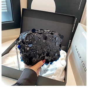 Close-up of black sequin crossbody bag with silver chain strap and premium gift box