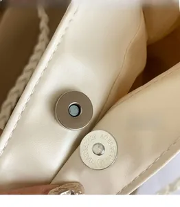 Detail of silver magnetic buckle with precision engraving on off-white tote bag