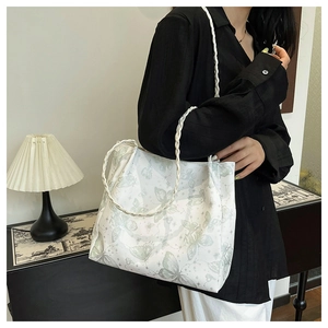 Close-up of white canvas tote bag featuring green butterfly print and woven rope handles