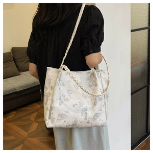 Detailed shot of white tote bag with butterfly print and woven braided shoulder strap