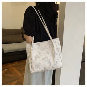 Side view of a large white tote bag with butterfly prints and woven rope handles