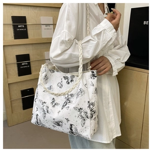 Detail of white tote bag featuring black butterfly prints and woven rope handles