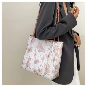 Detail of pink woven rope straps on a large tote bag with butterfly prints