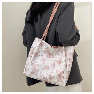 Detail view of the pink butterfly print on a white tote bag worn by a model in casual style