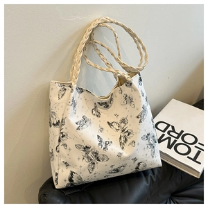 Close-up of butterfly print detail and woven faux leather handle on white tote bag