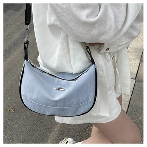 Close-up of a light blue crescent hobo bag featuring black trim and silver logo detail