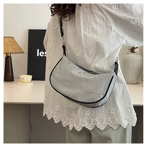 Detailed view of light gray pleated dumpling bag with crescent shape and black shoulder strap