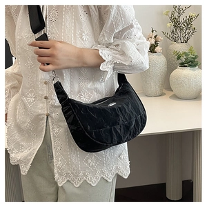 Detail of black crescent crossbody bag with pleated texture and adjustable strap
