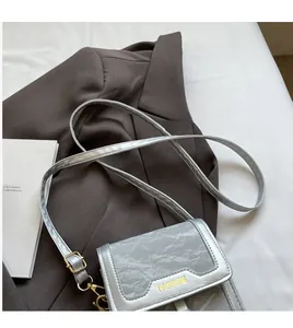 Close-up of metallic silver crinkle texture crossbody bag with gold fashion lettering